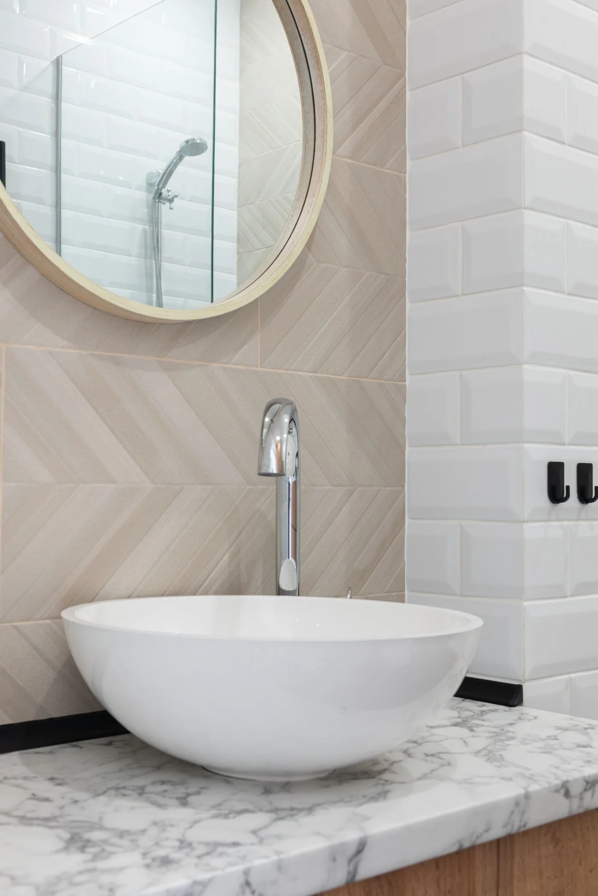 Bright bathroom with a white ceramic basin, chrome tap, pale tiles and a marble countertop